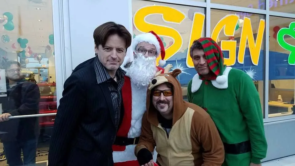 Collaborators gathered with holiday performers outside a colorful storefront