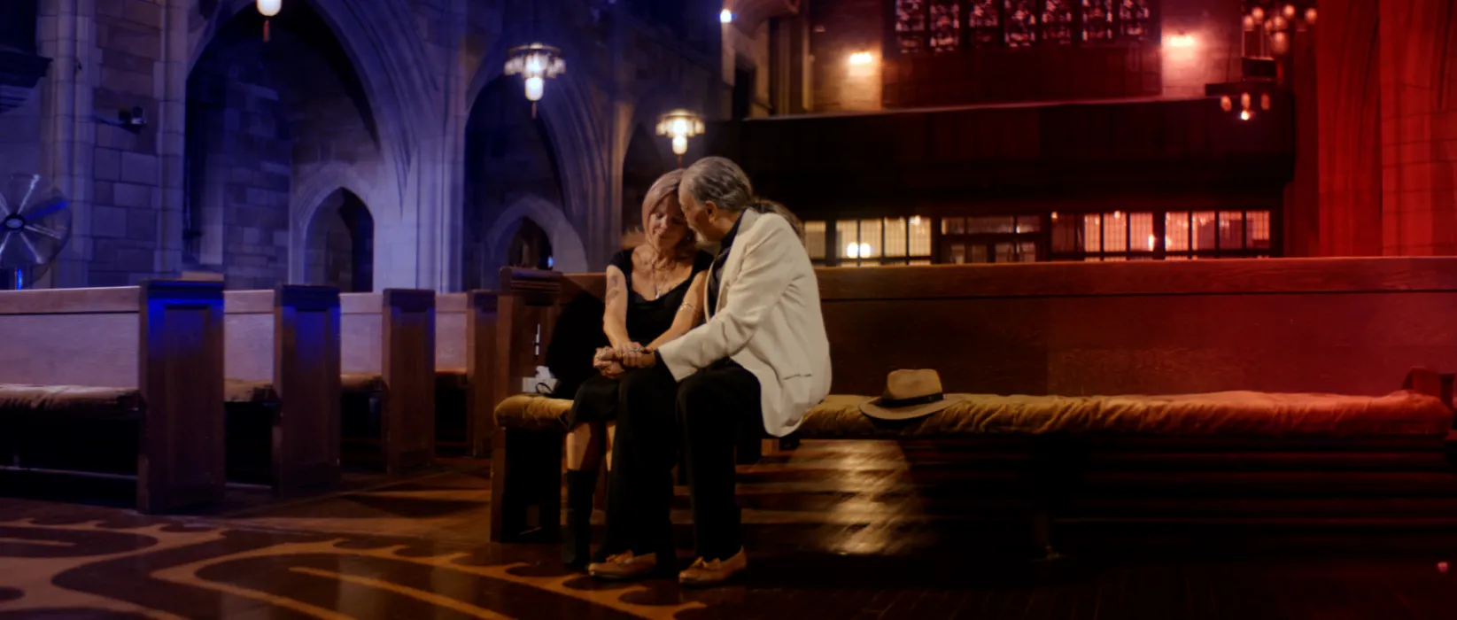 A warmly lit production scene with collaborators seated in a dark interior