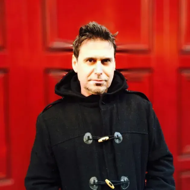 Portrait of JD Shapiro in front of a red door